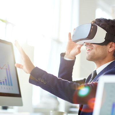 Happy manager with virtual reality goggles touching imaginary world